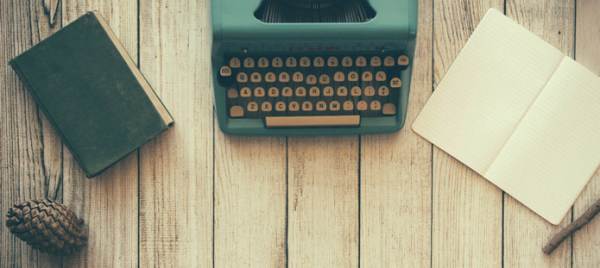 A photo of a book, typewriter, and notebook