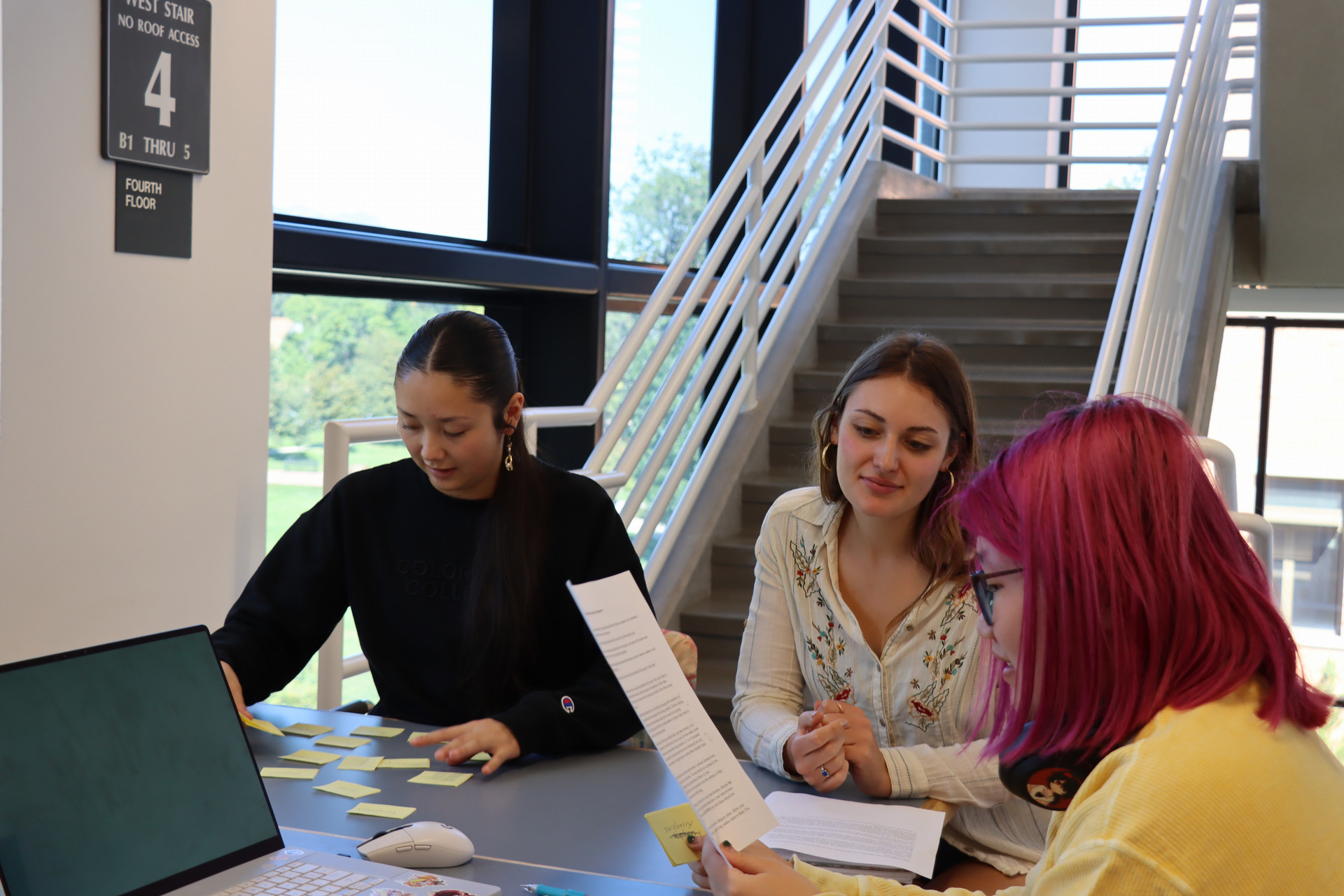 Students working together on an assignment by a stairwell