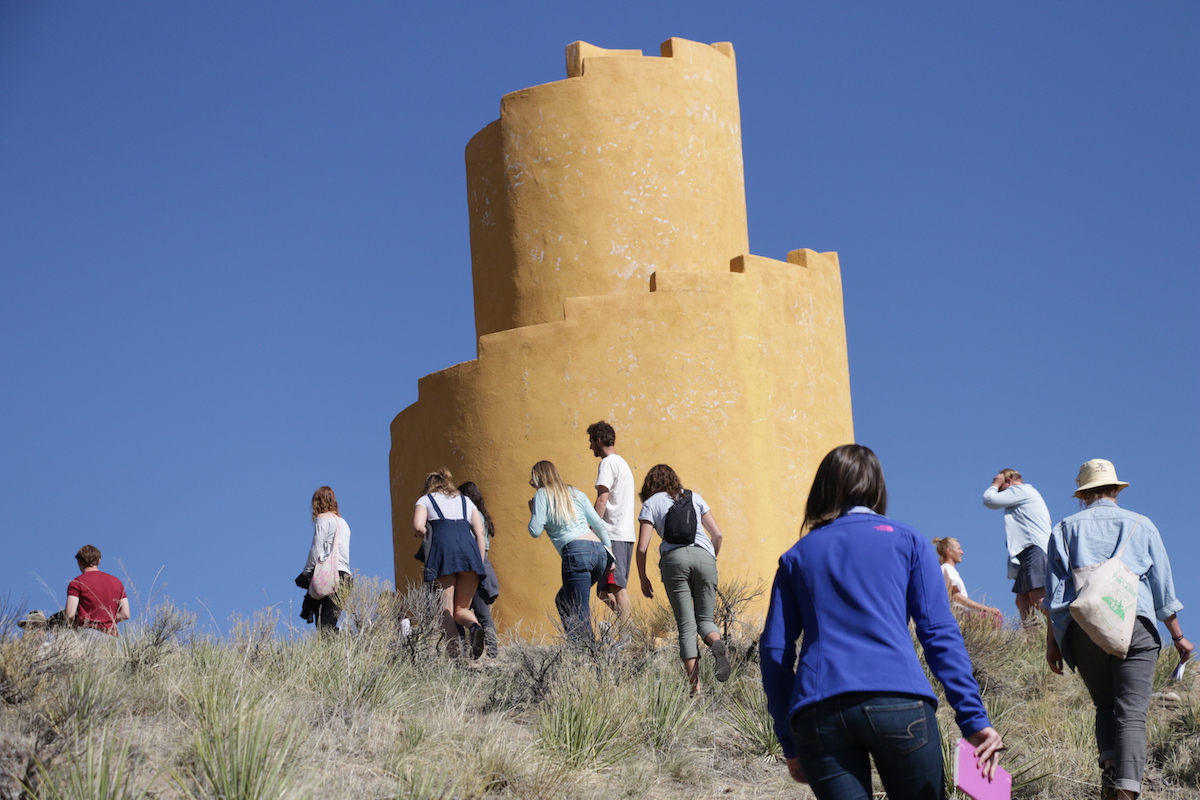 Students hiking past some Pueblo architecture