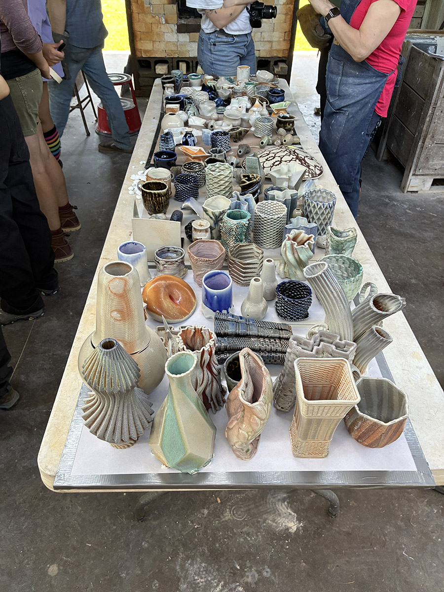 Finished ceramic pieces in a long table with people standing around it