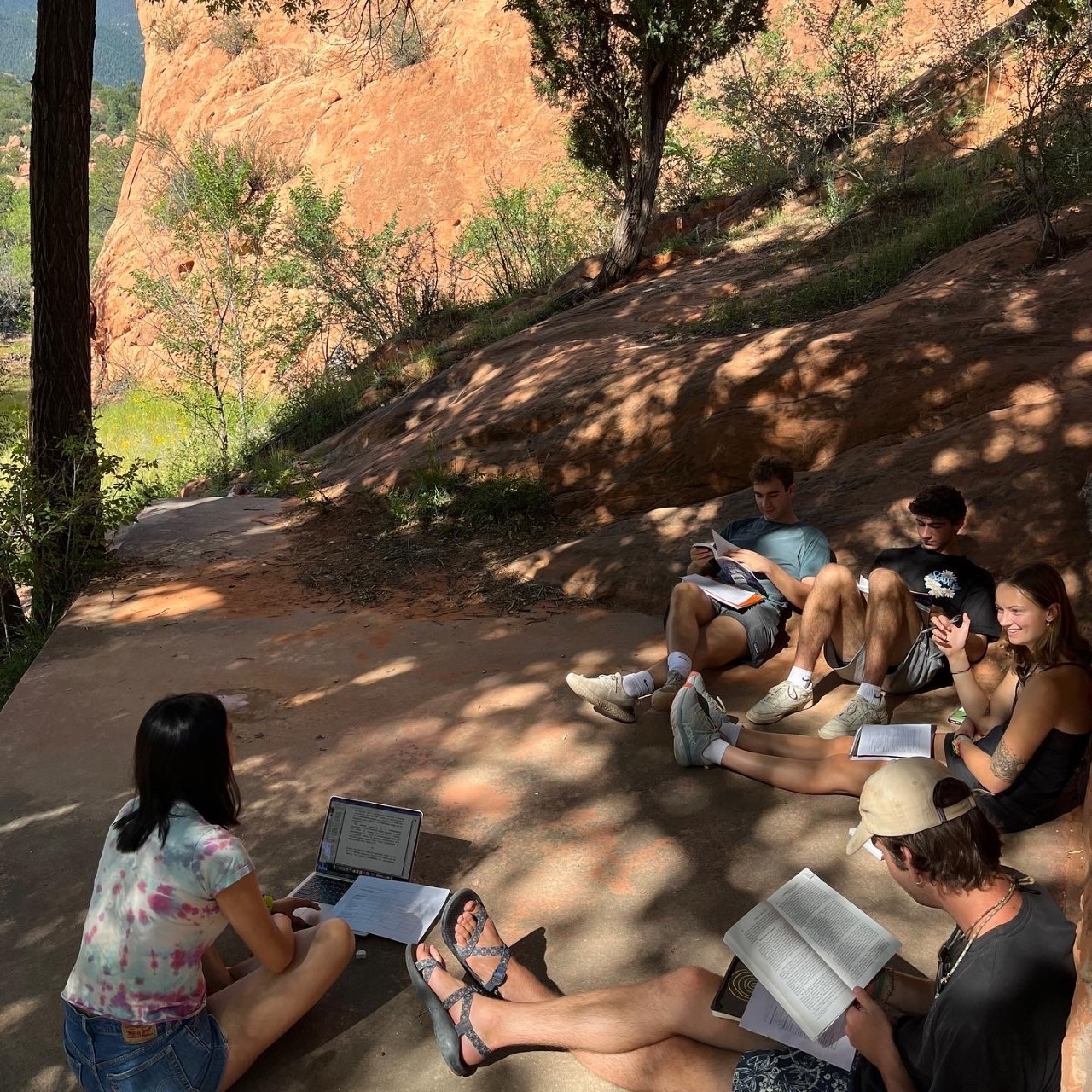 students with their laptops and book discussing their readings in the shade in Red Rocks Open Space