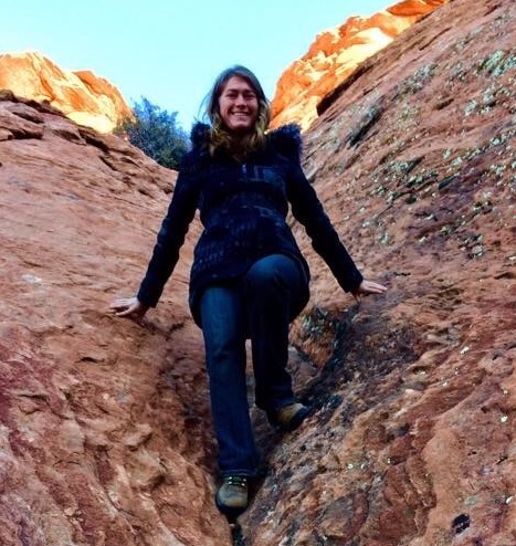 Justine smiling and sitting on rocks