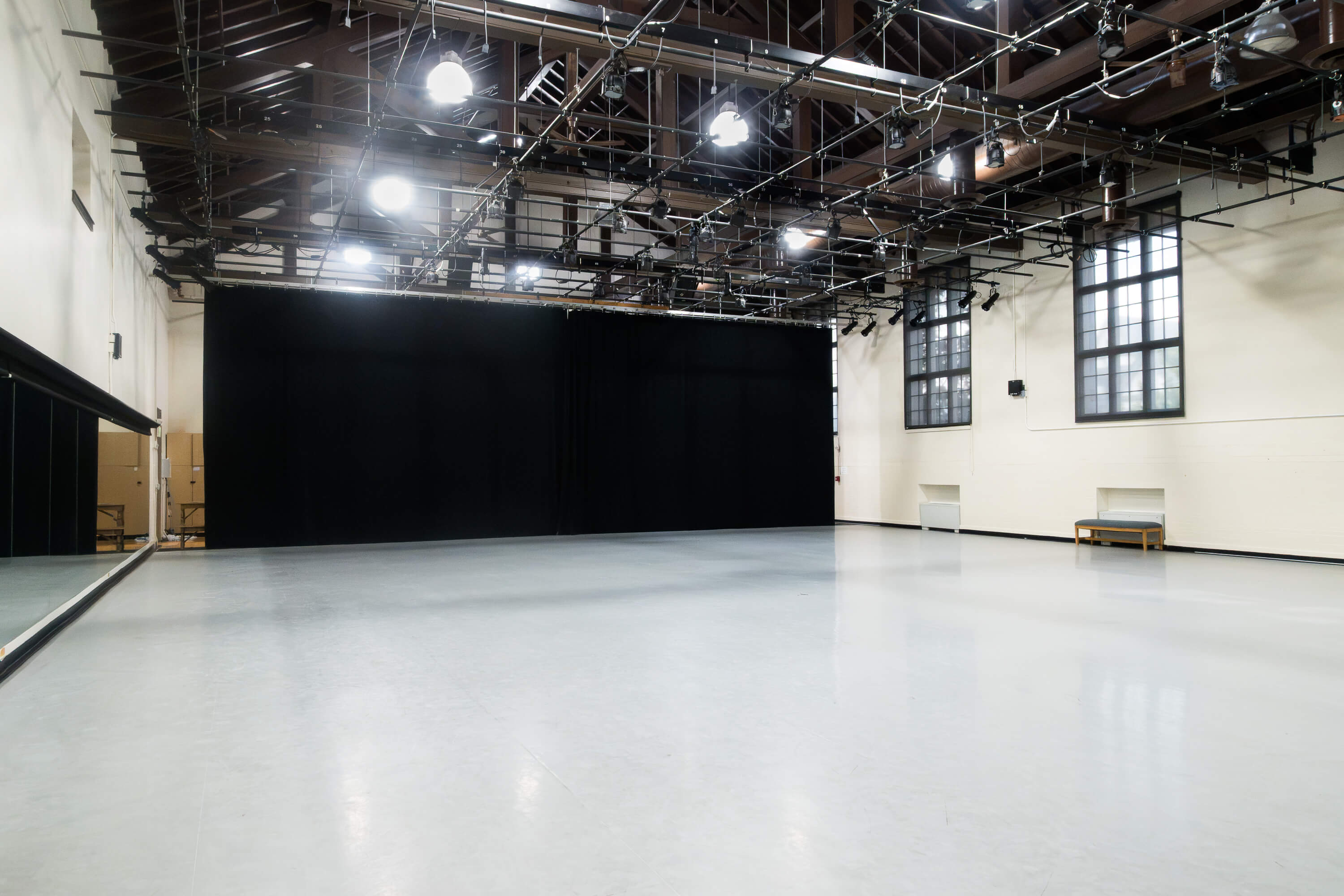 Interior of the Cossitt Gym, featuring a large open dance floor, mirrored wall, black curtains, and extensive overhead theatrical lighting.