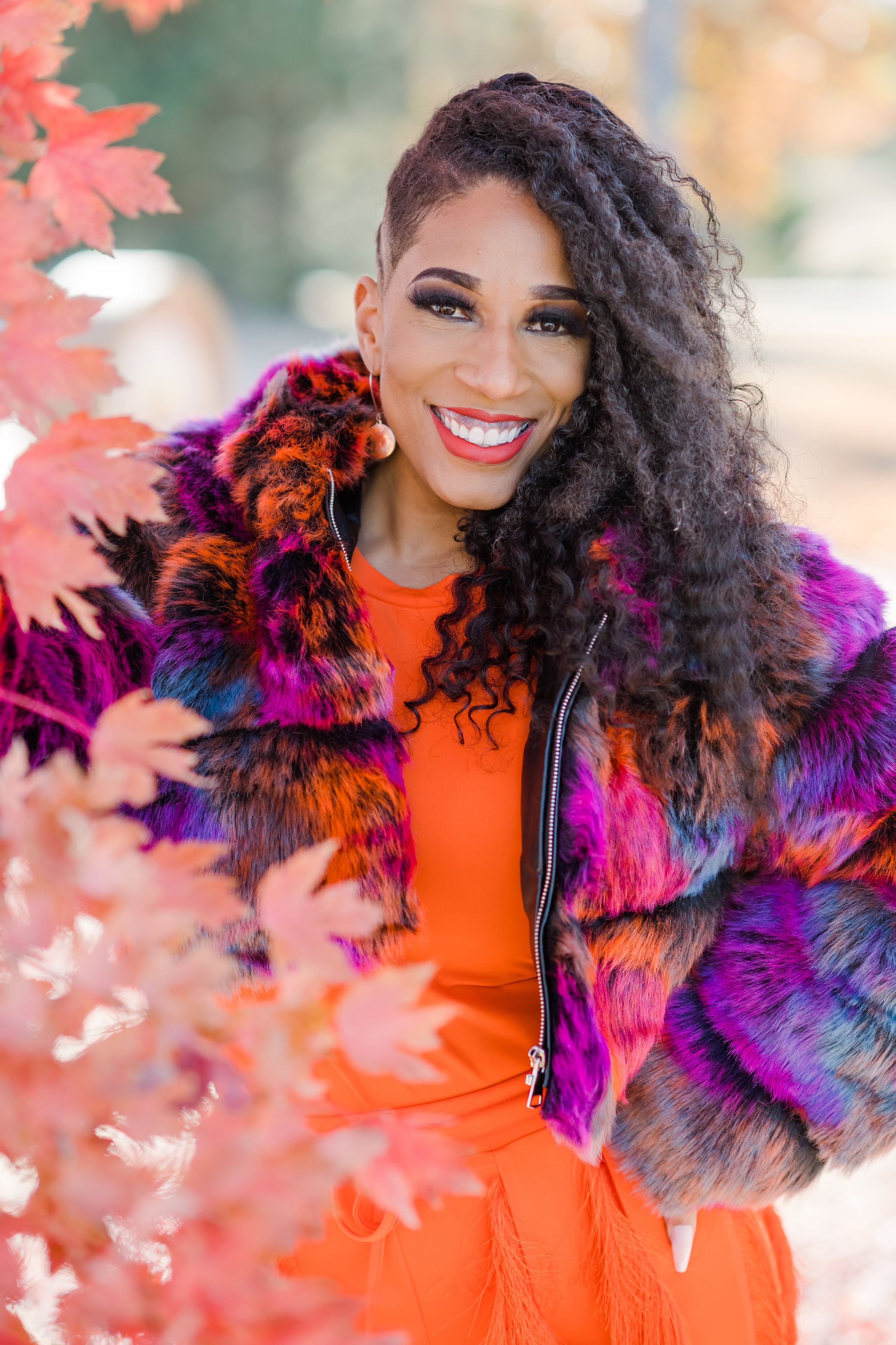 Latisha Hardy in a colorful coat and orange dress, smiling at the camera.