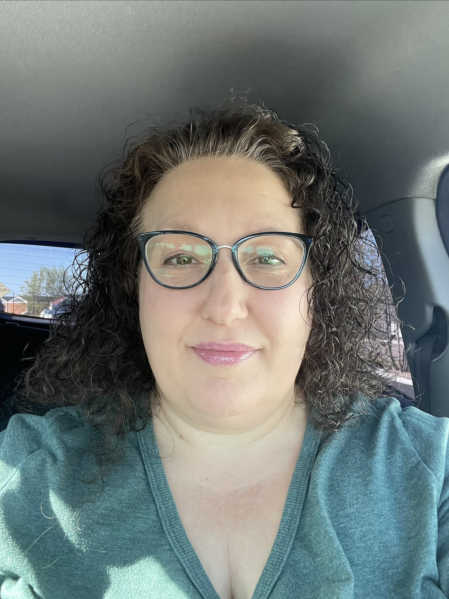Kristen Wickersheim smiling at the camera, wearing glasses and a teal top.