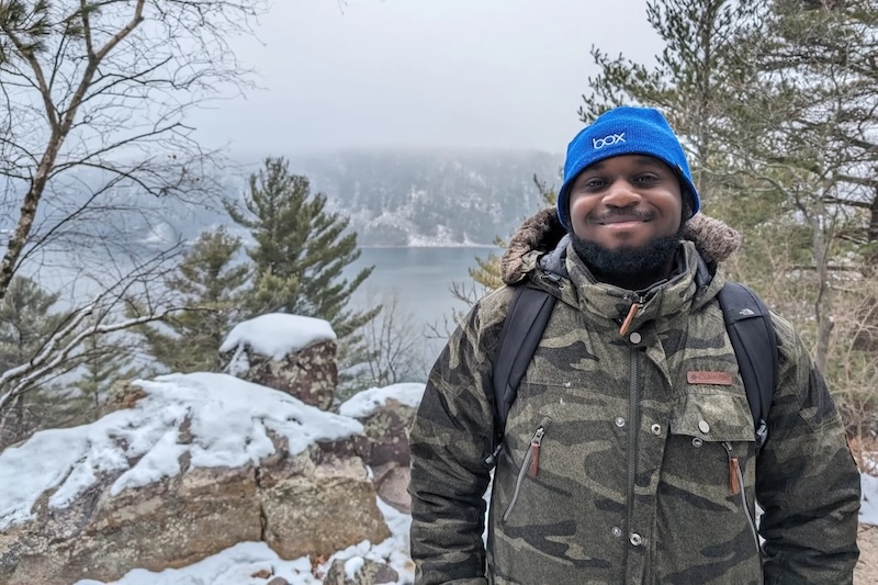 John Capers smiles for the camera in a snowy woodland mountain scene