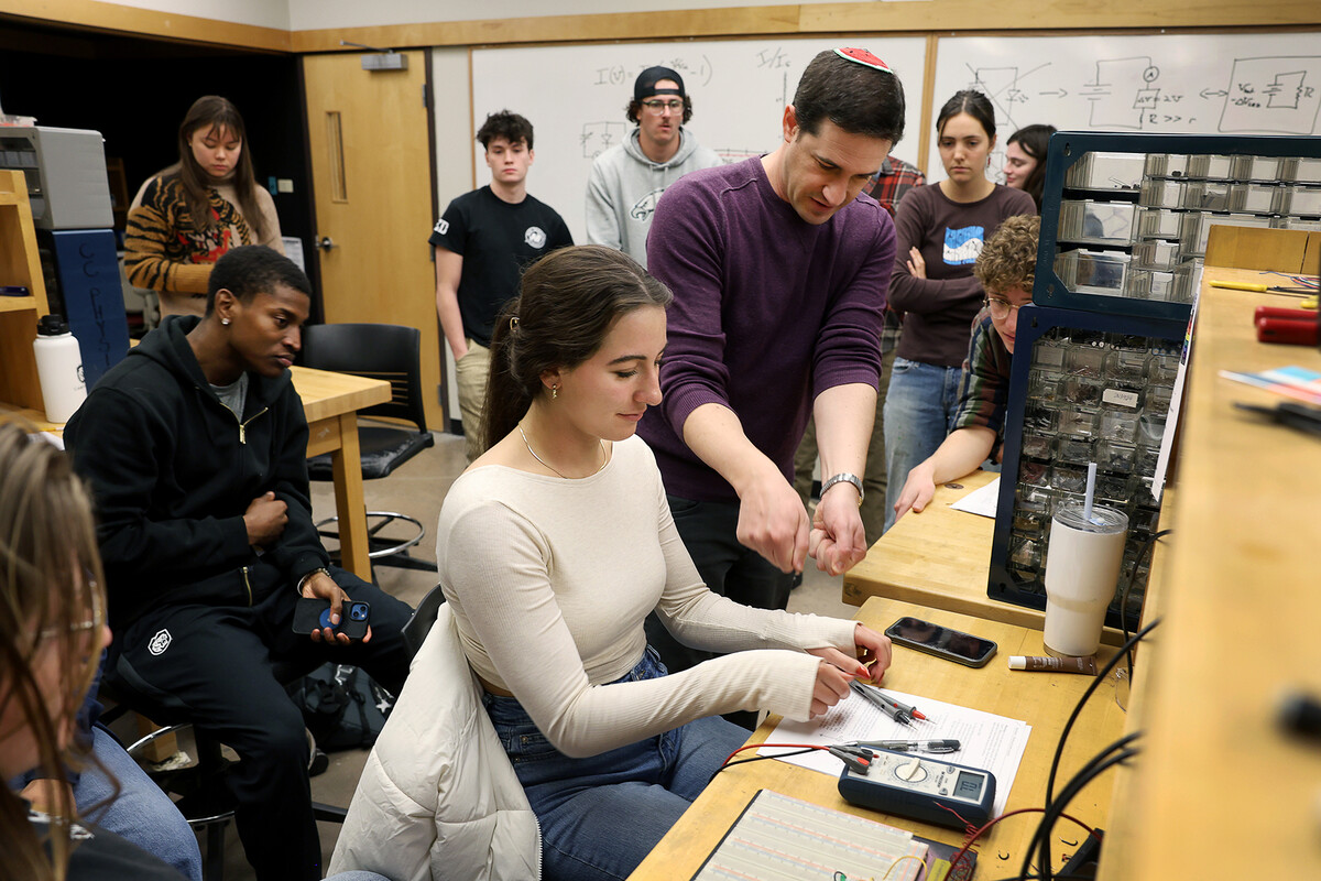 Prof. Adam Light teaching Physics inside Barnes Science Building. He's showing a student how to use a multimeter on a breadboard.