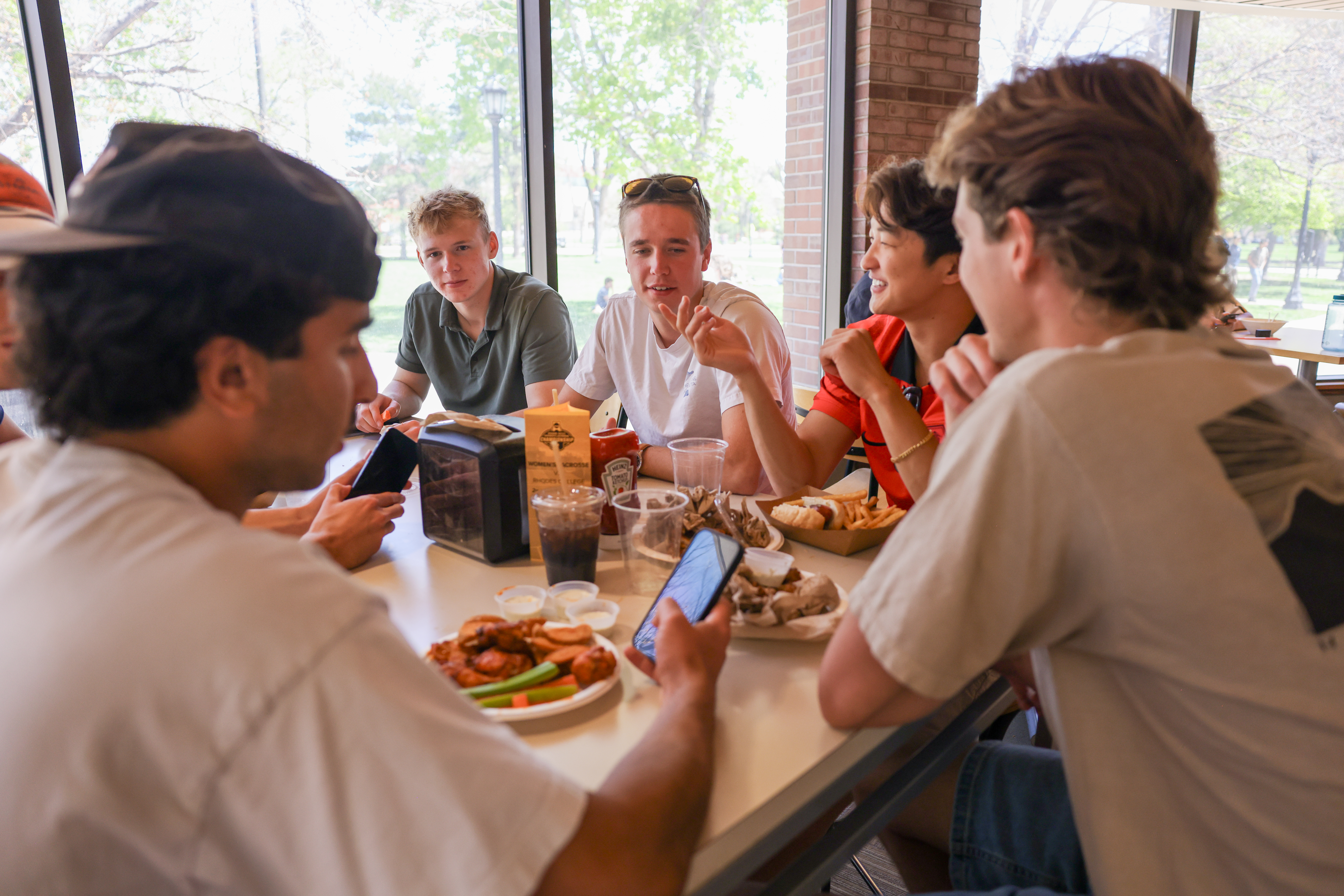 Group of students gathered around a table, sharing a meal in Rastall dining hall.
