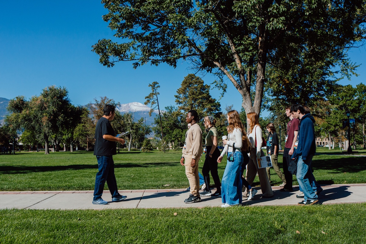 Current CC student leading prospective students on a campus tour. Mountain views in the background.