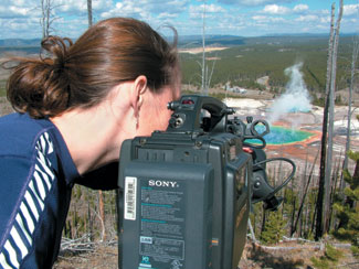 <strong>Katy Garton ’01</strong>, a graduate student in science documentary filmmaking, peers through her viewfinder to find the best angle for filming the Grand Prismatic Spring in Yellowstone National Park