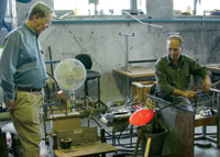 
<strong>Bill Geary ’62</strong>, left, looks on as master glass blower Jon Bejer works in his studio. Bill and his wife, Margareta, relocated to Vastervik, Sweden, where Bill has entered into a contract to design production glass for a Swedish glass company, Skruf Glass Works. He also consults for the Vastervik Museum, continues his glass appraisal services, and contributes annual written documentation of Nordic glass values for the publication “Schroeder’s Antiques Price Guide.”
		