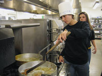 
Chloe Benson ’09 </strong>flips latkes to serve at Chaverim/Hillel’s table at a December interreligious event, while <strong>Liana Singer ’07</strong>, in the background, waits to shuttle them out to waiting students in the Worner Center. Hillel is CC’s Jewish student organization. Photo by <strong>Elizabeth Kolbe ’08</strong>. 		 