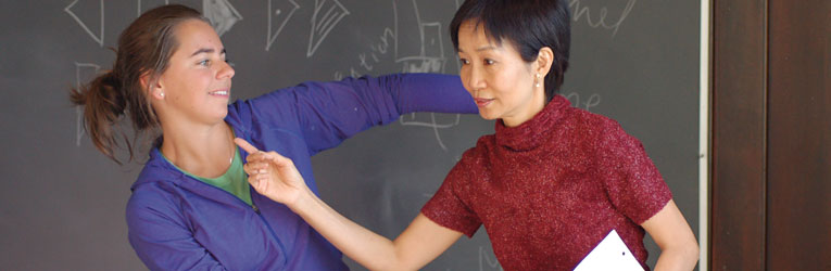 
		Wang helps Christine McGarvey '07 refine her motions; the blackboard behind them shows Labanotation symbols. Photo by Anne Hatch.	