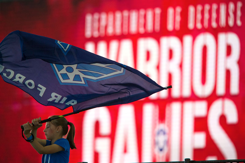 A girl waves an Air Force flag to support athletes competing in an air rifle competition during the 2018 DoD Warrior Games at the Air Force Academy in Colorado Springs, Colo. June 5, 2018. (DoD photo by EJ Hersom).