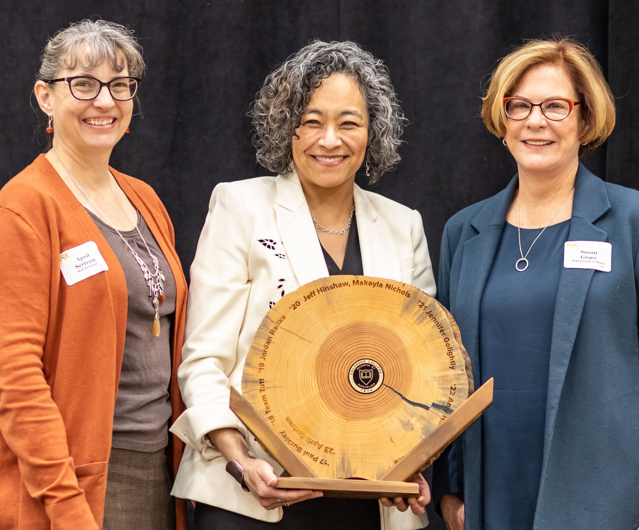 L. Song Richardson presents the Presidential Award for Collaboration and Community Building to Susan Grace, right, and April Scriven, who tied for the honor. Presidential Award trophies are made from reclaimed wood from trees taken down in the renovation and expansion of Tutt Library. Grace will have her name engraved on the wood.