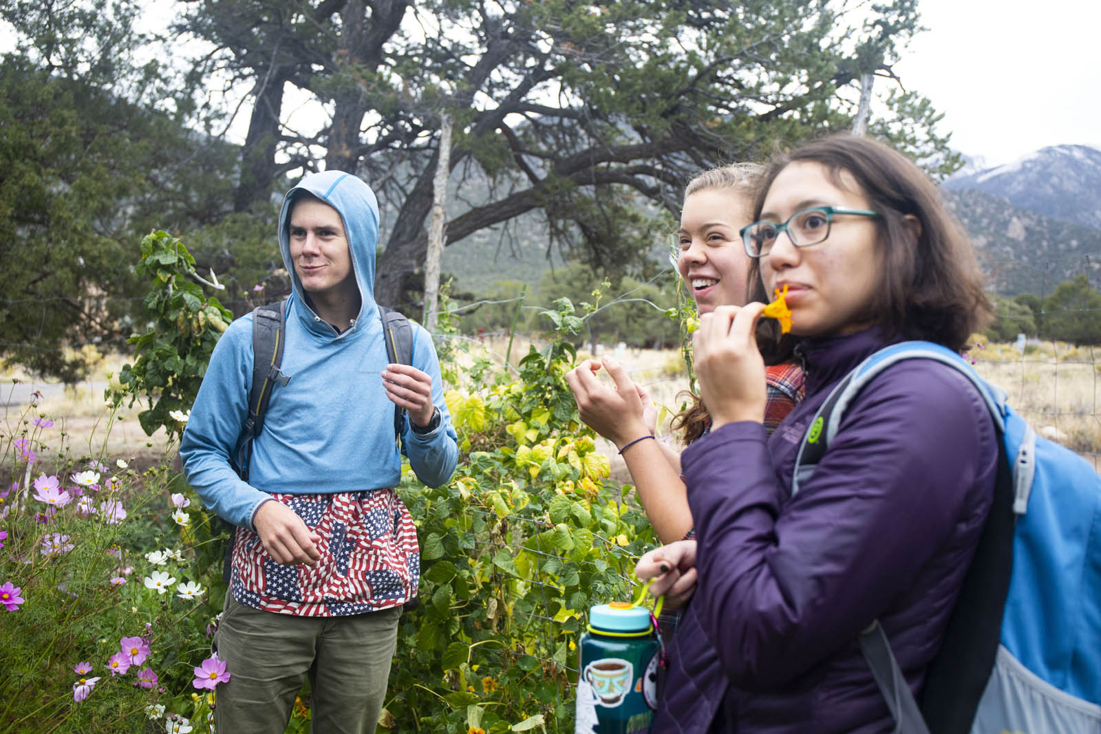 <strong>Elliot Nelson '22</strong>, <strong>Fiona Swope '22</strong>, and <strong>Clara Martinez Dunbar '22</strong> taste a spicy flower that is edible while visiting a Crestone, Colorado, gardener’s garden during their FYE class on sustainability.