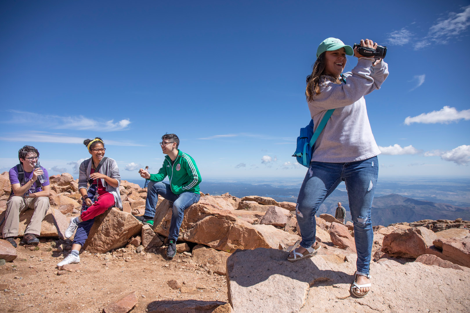 <strong>Maddy Brauninger ’23</strong> films from the summit of Pikes Peak while classmates <strong>Ian Widmann ’23</strong>, <strong>Kiara Butts ’23</strong> and <strong>Danny Zamudio ’21</strong> discuss access to the outdoors and their Pikes Peak experience. Photo Jennifer Coombes