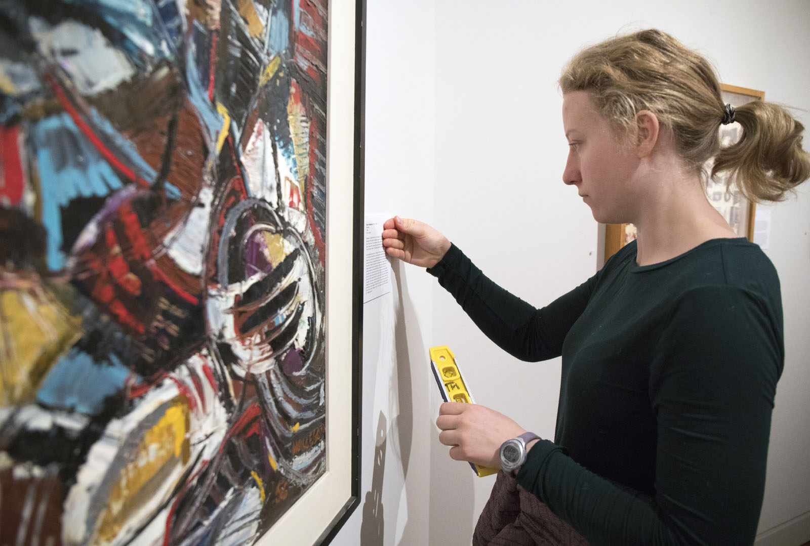 <b>Anna Gauw '21</b> measures the wall so that she can determine where to place her description plate that she wrote for the FYE curated exhibit at the Fine Arts Center.