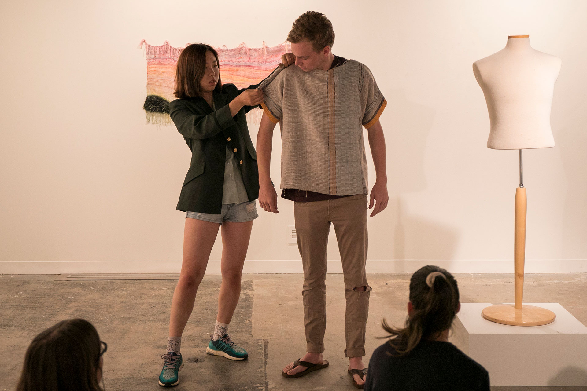Yangfan Yue '21 adjusts the sleeve of a shirt that Charley Dickey '19 wove in the Fiber Arts Summer Session class during a final exam discussion and critique in Coburn Gallery before a show of the work completed by students in the class.