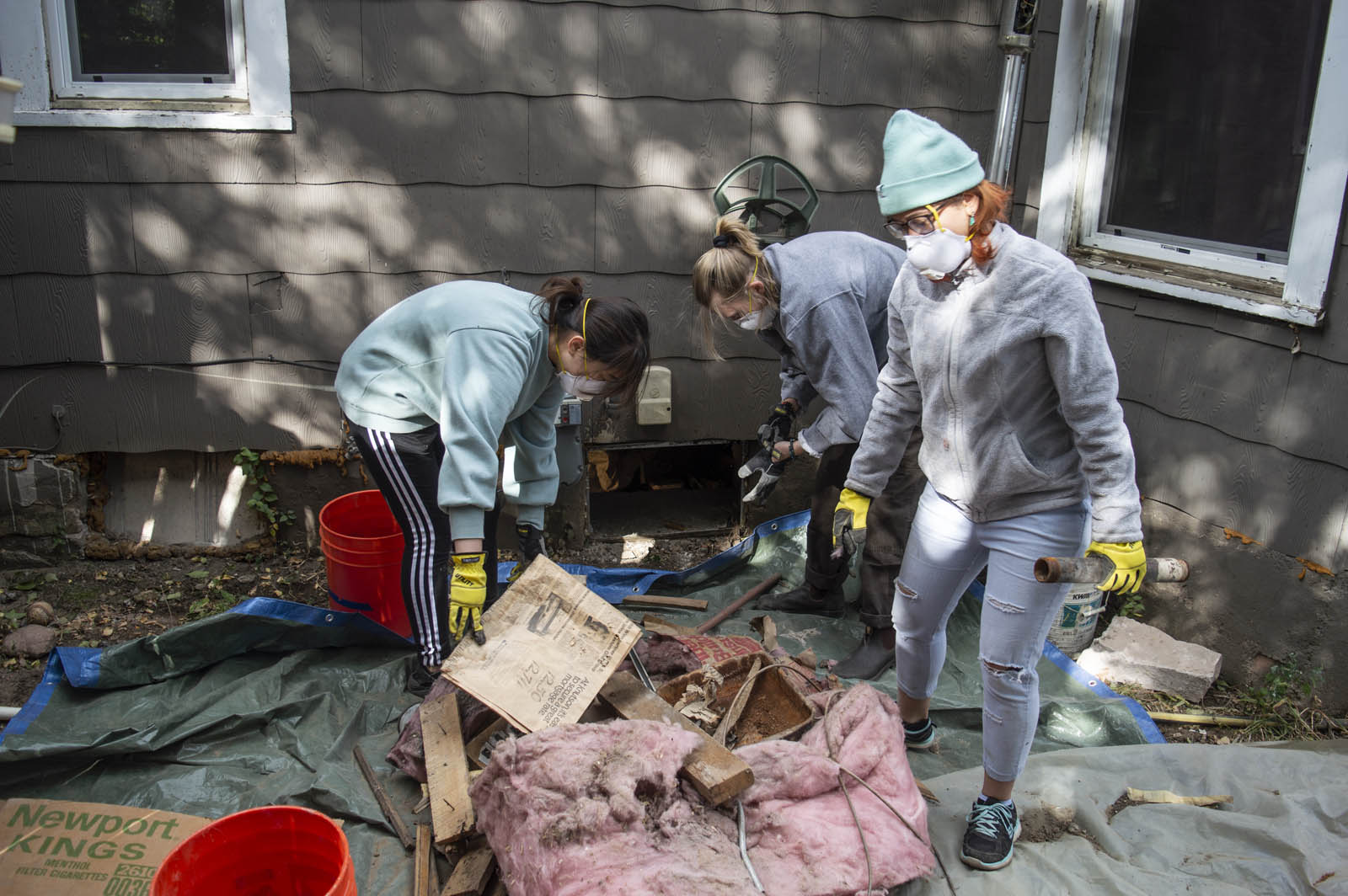 <b>Tiantian Zhu ’22</b>, <b>Frannie Nelson ’21</b>, and <b>Fai Chanchai ’20</b> remove debris from a home’s crawl space before laying new insulation. The three helped retrofit a house in the community as part of their coursework in a CC class titled Energy: Environmental Thermodynamics and Energetics. Photo by James O’Brien/ERC