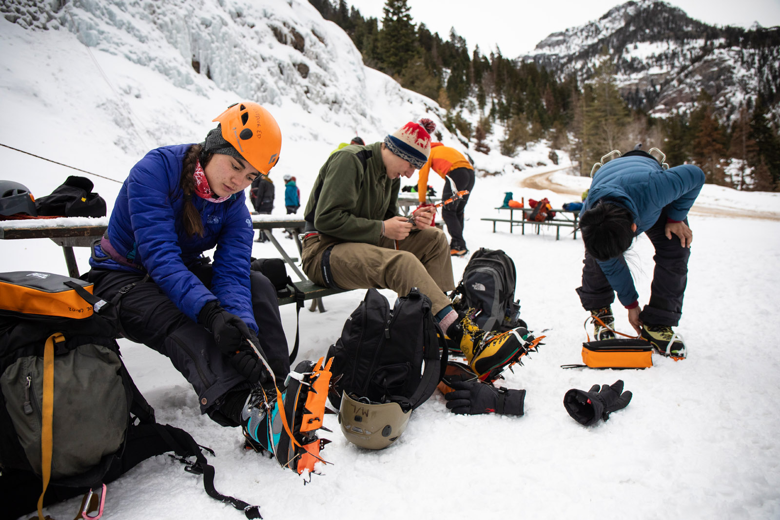 <strong>Kaila Ablao ’21</strong>, <strong>James Hanafee ’22</strong> and <strong>Saria Sato Bajracharya ’20</strong> learn how to attach their crampons to the snow boots they need in order to enter the ice park. The blades on the crampons are necessary not just for climbing the large ice-covered rock faces but also for safely hiking on the mountain trails in the park. Outdoor Education took students new to ice climbing to the Ouray Ice Park in Ouray, Colorado during a block break trip. The low-cost trip is designed for students who are new to ice climbing and might not otherwise be able to try out the sport due to the investment required to take lessons and purchase or rent equipment.