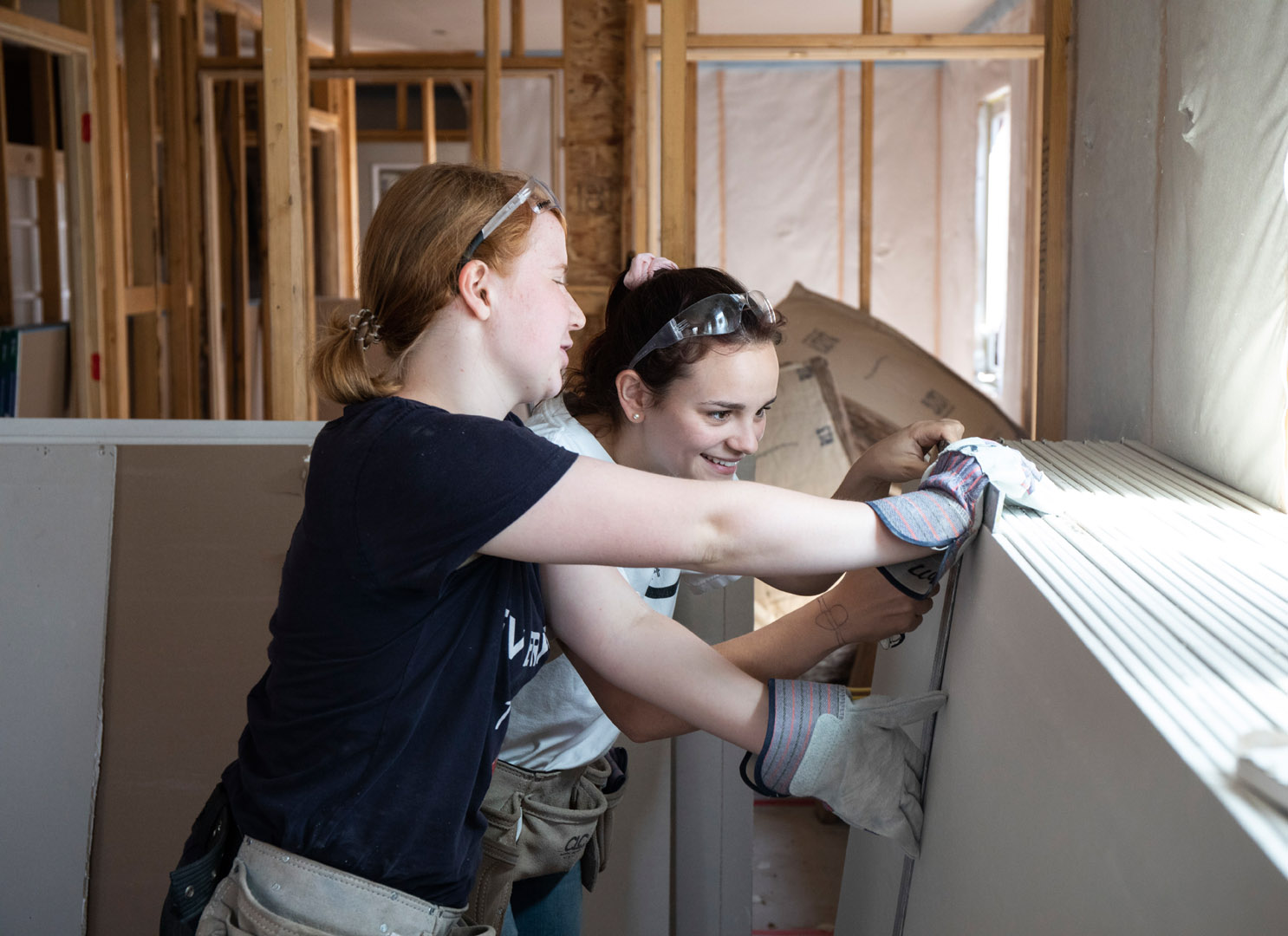 Rabea Friedrich and Meg Westmoreland measure and mark a piece of drywall to cut. For their Priddy Trip experience, freshmen traveled to Santa Fe, New Mexico where they worked with Habitat For Humanity putting up drywall for homes that will eventually be turned over to recipients. Photo by Jennifer Coombes