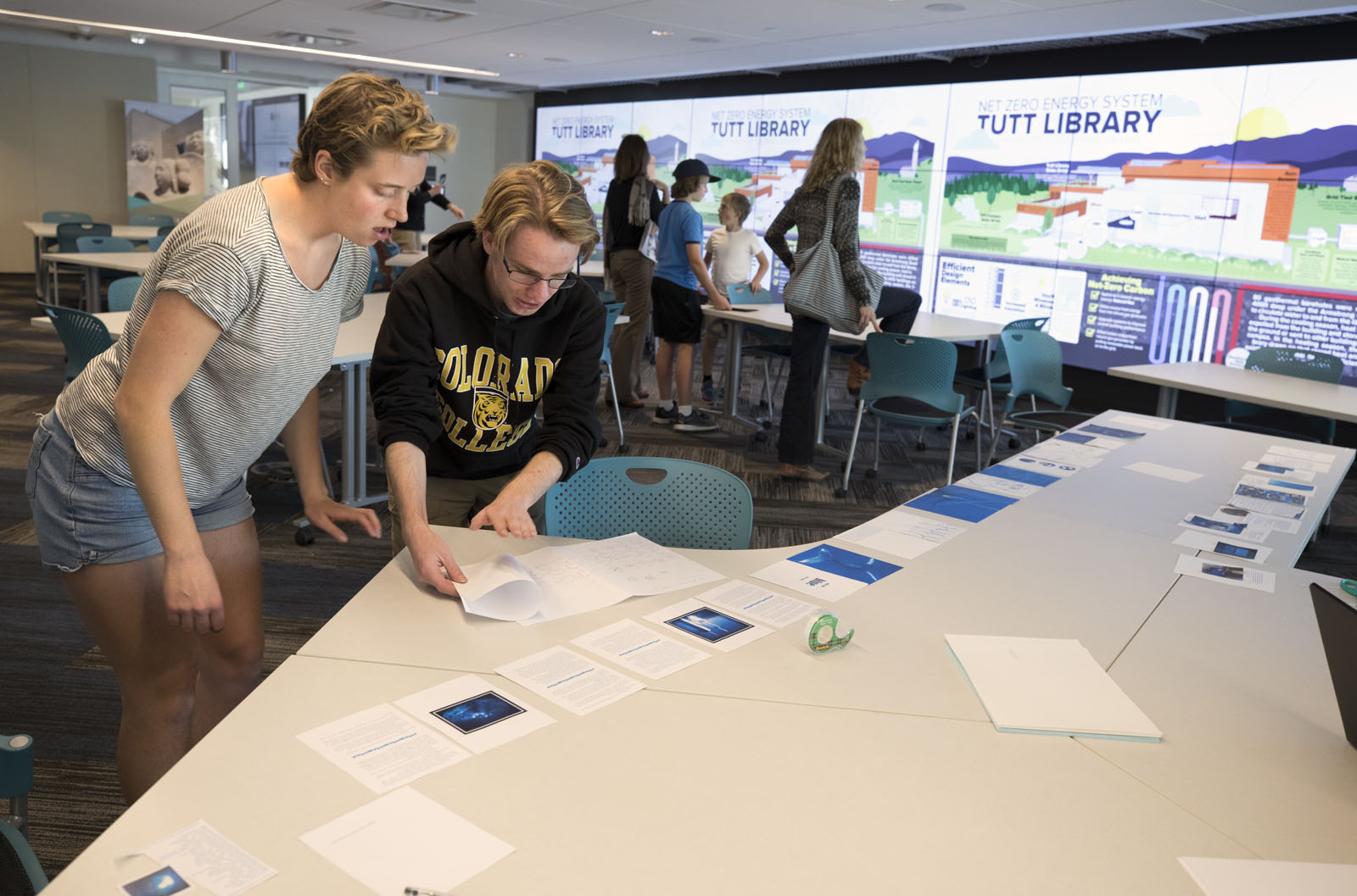 Students work on a final project for class as visitors check out the Net Zero display on the Ryan Data Visualization Wall.