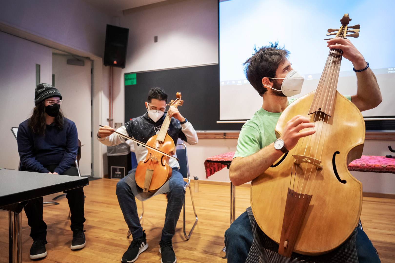 Right to left: Chris Heckenkamp ’23 plays bass viola da gamba and Marco Tapia ’22 plays tenor viola da gamba as assistant Ian Widmann watches. Photo by Lonnie Timmons III 