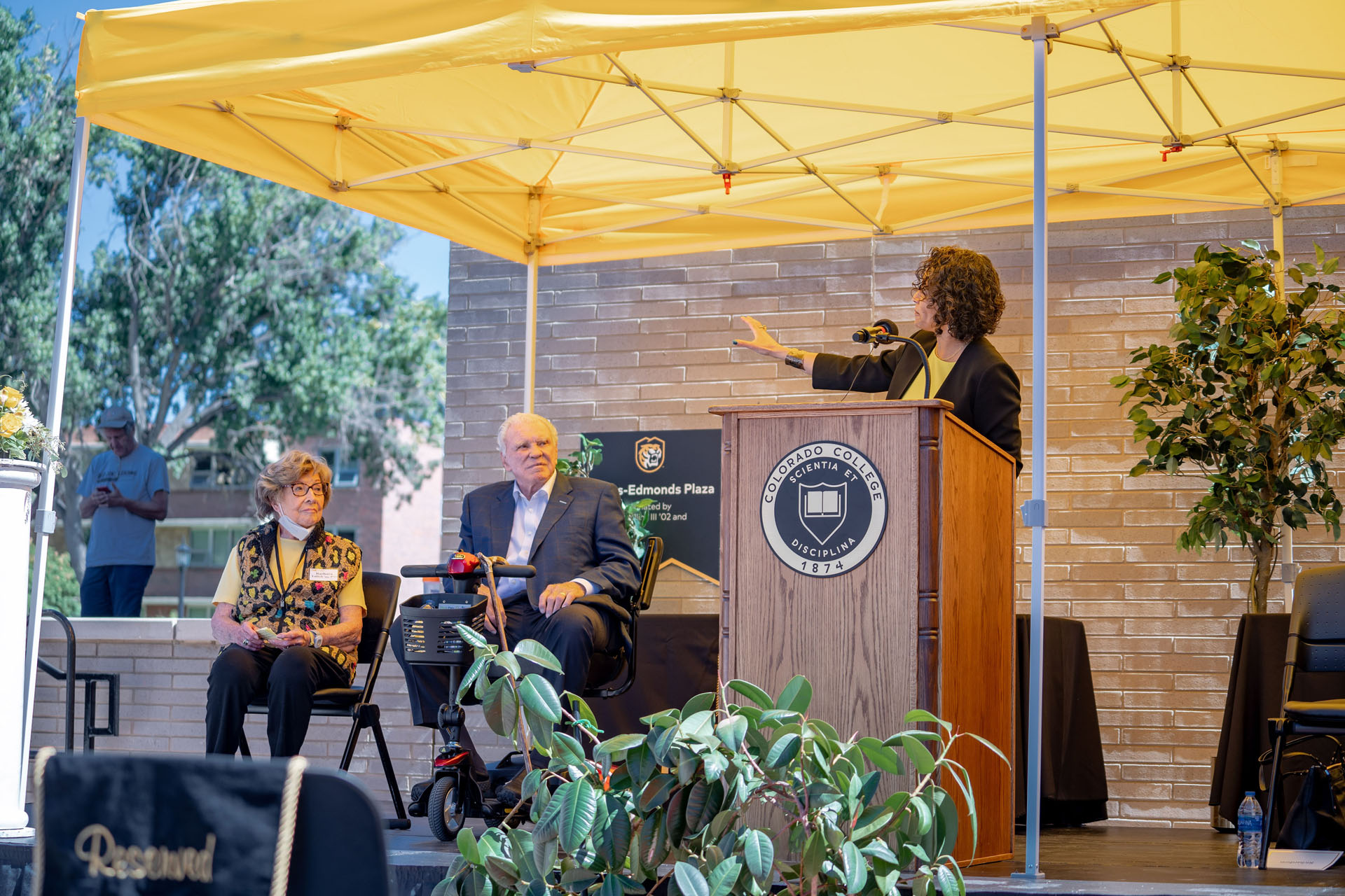 CC celebrated the opening of the new Ed Robson Arena and Yalich Student Services Center with a ribbon-cutting ceremony and remarks from President L. Song Richardson (standing) and building namesakes <strong>Barbara Yalich ’53</strong> and <strong>Ed Robson ’54</strong> (both seated) on Saturday, Sept. 18. Photo by Gray Warrior.