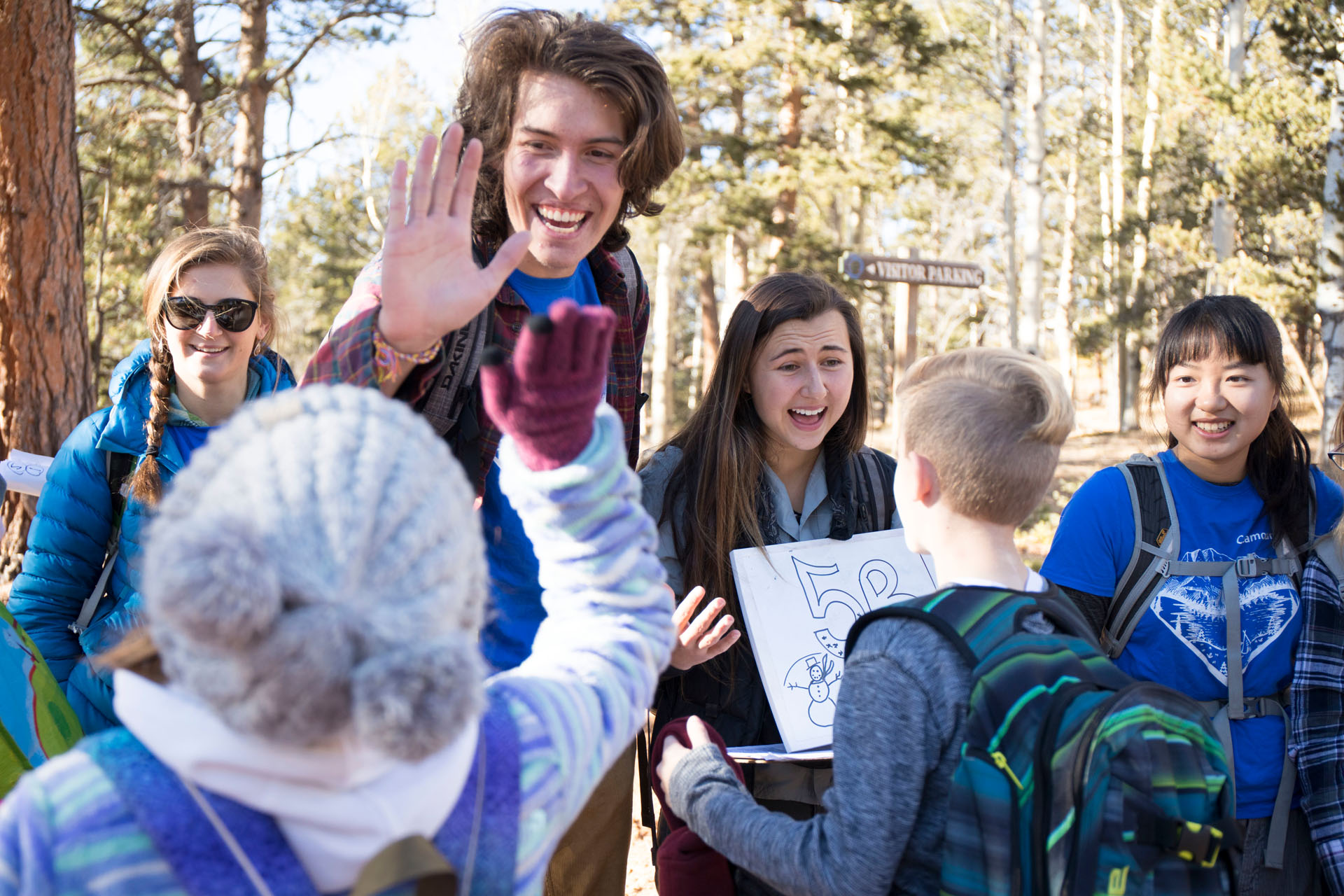 *Please note: this photo was taken in Fall 2017, prior to the COVID-19 pandemic. <strong>Daniel Allen '20</strong> high fives a student while <strong>Olivia Martinez '20</strong> and <strong>Aiyu Zheng '19</strong> greet students for their last day of outdoor school. Photo by Jennifer Coombes.