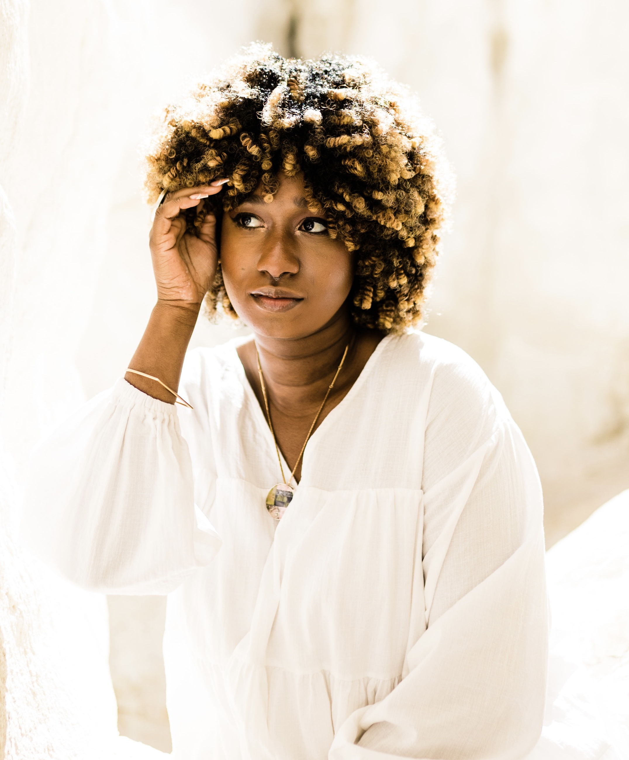 Irina Amouzou, a black femme person,  in a white shirt with a bright background