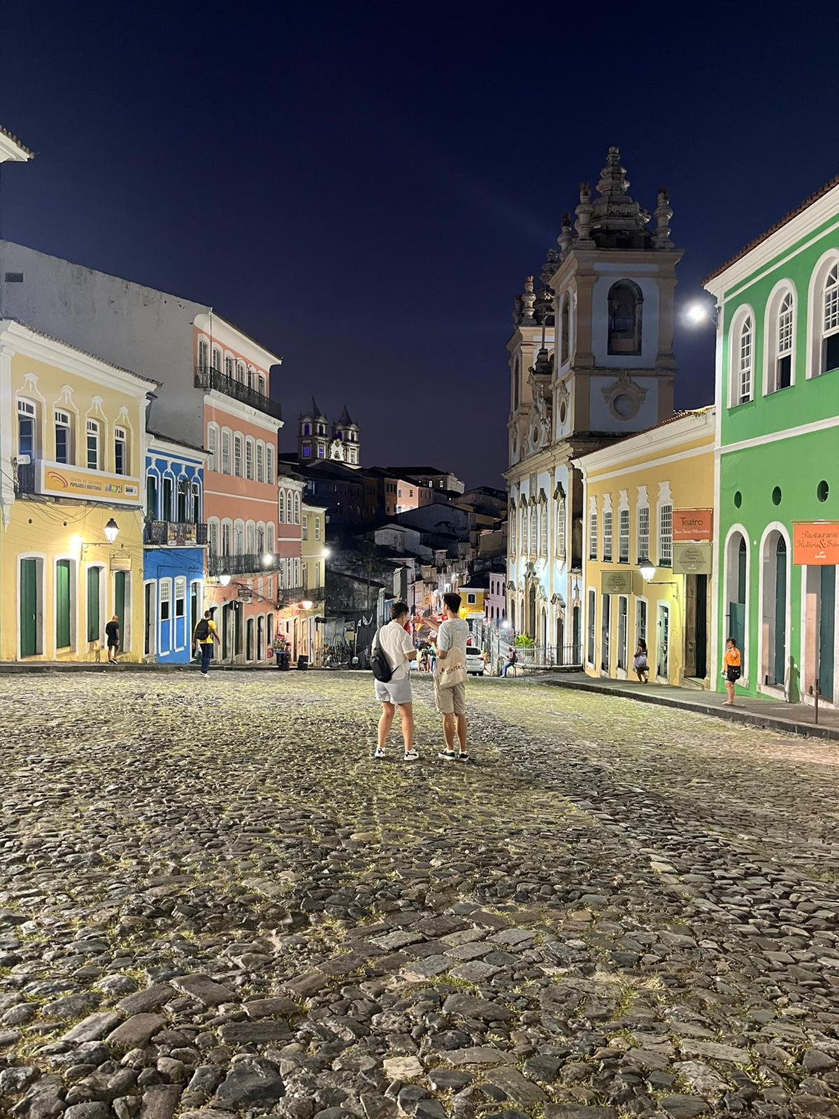 Two people standing between brightly colord buildings in Salvador, Brazil