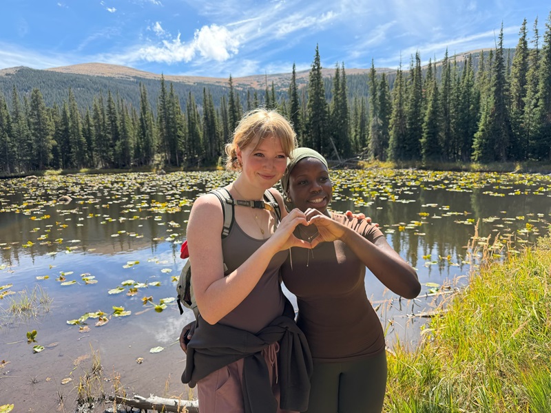Two participants of the Wild Basin FOOT trip making a heart with their hands. 