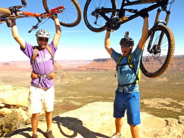 two people lifting their moutain bikes above their heads