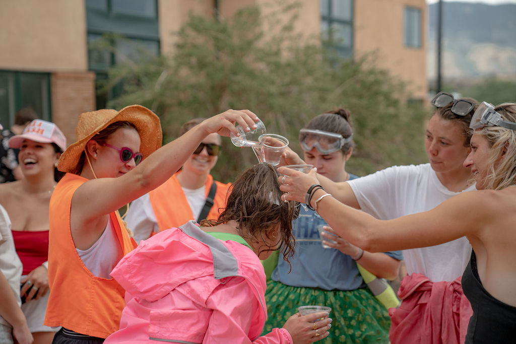 A group of students pouring water on the head of another student while waiting in line at the senior BBQ <span class="cc-gallery-credit">[Gray Filter Photography]</span>