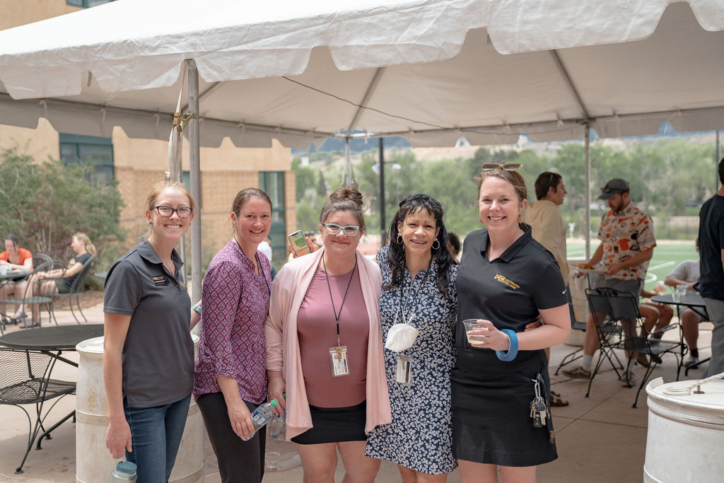 A group of staff members posing for the camera outside at the senior BBQ <span class="cc-gallery-credit">[Gray Filter Photography]</span>
