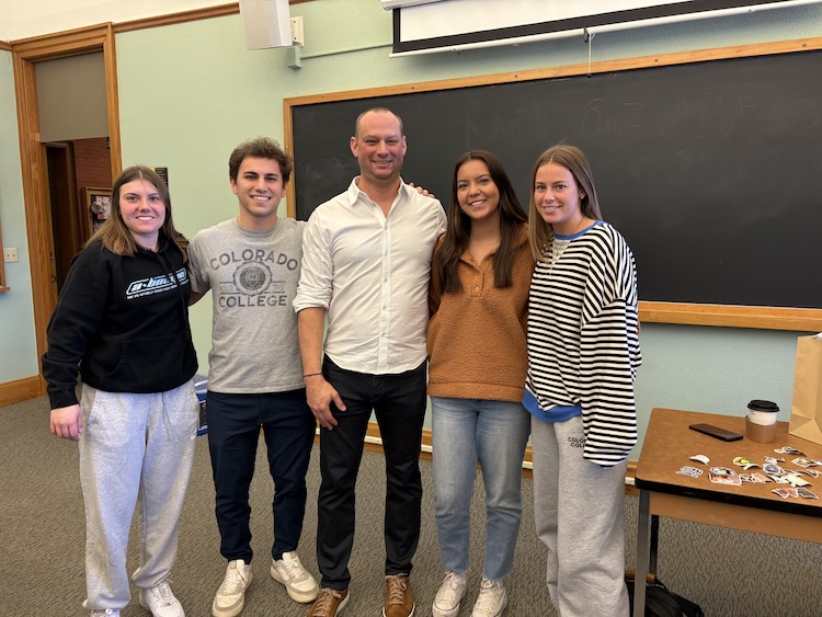 Trimble Vice President Chris Peppler poses with 4 students at the front of a CC classroom